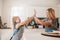 Little girl and her mother in kitchen giving high five