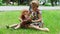 Little girl and her mother read book on lawn