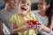 A little girl with her parents posing for a photo with a bowl full of cherry tomatoes at home. Family, breakfast, together, home