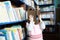 Little girl hide behind book in library environment