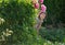 Little girl hiding in the garden behind the peony bushes