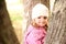 Little girl hiding in the trees in autmn park
