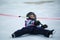 Little girl in hockey equipment falling down in ice rink