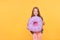 Little girl holding a big donut over yellow background.