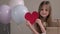 Little girl holding big red paper heart surrounded by zero waste gifts and air balloons. Valentines Day, love, mothers