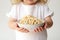 A Little Girl Holding A Bowl Of Noodles