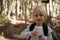 Little girl holding bubble wand in her hand in the forest on a sunny day