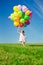 Little girl holding colorful balloons. Child playing on a green