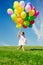 Little girl holding colorful balloons. Child playing on a green