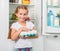 Little girl holding eggs near fridge