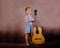 Little girl holding a guitar and showing a super sign with the second hand on a vintage background