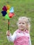 Little girl holding multicolored pinwheel in her hands.