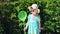 Little girl is holding scoop-net on background of green bushes in summer