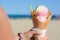 Little girl holding waffle cone with scoops of delicious colorful ice cream at beach on sunny summer day, closeup. Space for text