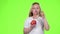 Little girl holds an apple in her hands and drinks juice from it. Green screen. Slow motion