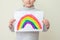 Little girl holds drawn rainbow