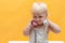 A little girl holds in her hands a tube from a wired telephone and looks around