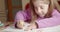 Little girl at home doing homework drawing on school`s book