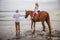 Little girl on a horse. Father leading horse by its reins on the beach. Horse riding by the sea. Family concept. Father`s day.