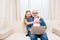 Little girl hugging happy grandfather using laptop at home