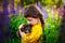 A little girl hugs her shepherd puppy in nature in a field with lilac flowers in the background. Tender love for a pet