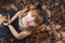 Little girl in the image of cats sitting on dry leaves.