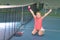 A little girl on an indoor tennis court is happy that she just won a tennis match. A little winner