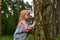 Little girl with interest explores a tree trunk outdoors