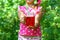 Little girl with jar of berry compote in the garden among the raspberry bushes, closeup. Authentic lifestyle image. Seasonal harve