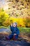 Little girl in jeans clothes happily throws autumn leaves