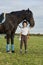 Little girl jockey communicating with her black horse in professional outfit