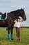 Little girl jockey communicating with her black horse in professional outfit