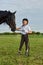 Little girl jockey communicating with her black horse in professional outfit