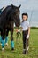 Little girl jockey communicating with her black horse in professional outfit