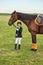 Little girl jockey lead horse by its reins across country in professional outfit