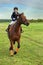 Little girl jockey riding a horse across country in professional outfit