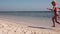 A little girl joyfully runs along the sea on the sand on the shore of Red Sea