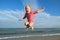 Little girl jumping and hovering in the air on the background of blue sky and summer sea. Happy child girl playing at beach and