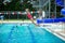 Little girl jumping off the diving board during her swim lessons at the local outdoor pool in the summer