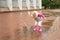 A little girl is jumping in puddles, flying drops of water