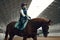 Little girl, kid, equestrian sitting in special uniform and helmet on horse, training on pavilion, learning horseback