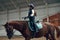 Little girl, kid, equestrian sitting in special uniform and helmet on horse, training on pavilion, learning horseback