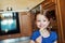 Little girl in the kitchen smiling, eating lollipop