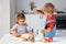 Little girl kneads dough on kitchen table at home with delight.