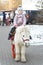 Little girl in a knitted hat and warm jacket rides a pony in a city park on a sunny winter day