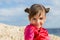 A little girl on with large swivel-eyed eyes is put and brushed japanesque smiles on a background a rock sea.