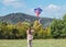 Little girl launching a colorful kite on the green grass meadow in the mountain fields. Happy childhood moments or outdoor time