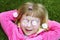 Little girl laying grass daisiy flowers in eyes