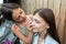 Little girl learn to do a makeup on her older sister, applying liquid tonal foundation on the face. Outdoor photo on