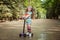 Little girl learn to ride scooter in a park on sunny summer day.